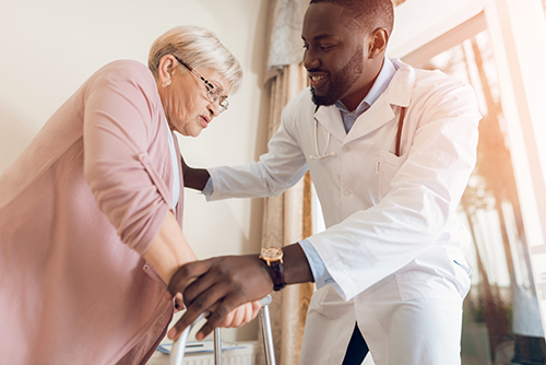 Doctor assisting elderly woman with walker